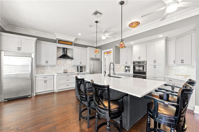 kitchen with white cabinetry, stainless steel built in fridge, sink, and wall chimney exhaust hood