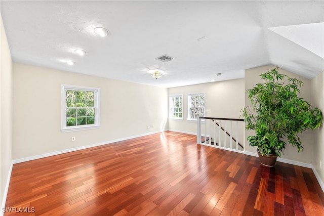 spare room with wood-type flooring, a healthy amount of sunlight, and vaulted ceiling