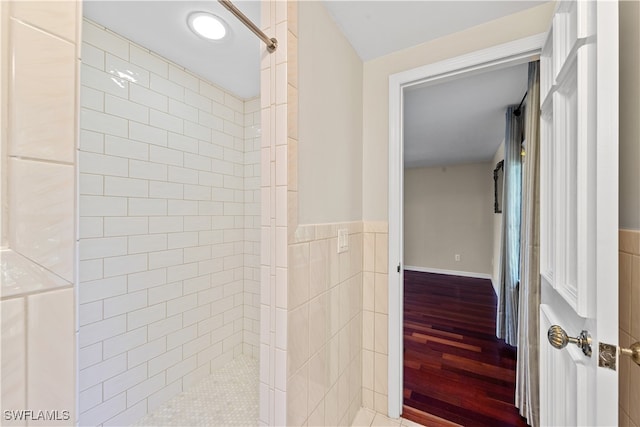 bathroom featuring tiled shower, tile walls, and wood-type flooring