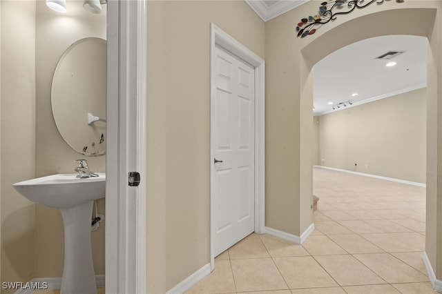 corridor featuring sink, light tile patterned floors, and ornamental molding