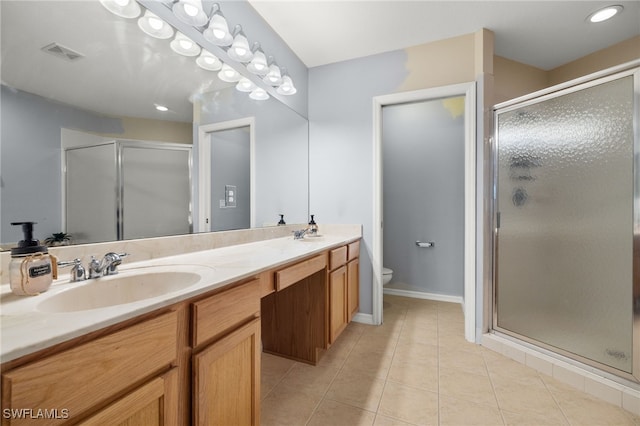 bathroom featuring toilet, vanity, tile patterned floors, and a shower with shower door