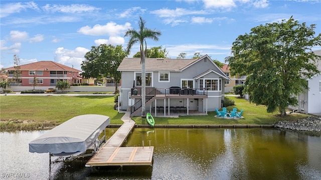 rear view of property with a deck with water view, a lawn, and a patio area