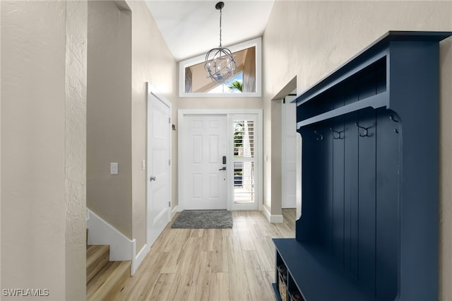 mudroom with high vaulted ceiling, an inviting chandelier, and wood-type flooring