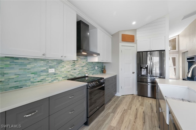 kitchen with white cabinetry, stainless steel fridge with ice dispenser, vaulted ceiling, electric range, and wall chimney exhaust hood