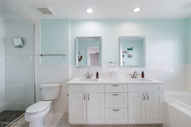 bathroom with tile walls, tile patterned floors, vanity, toilet, and a tub to relax in