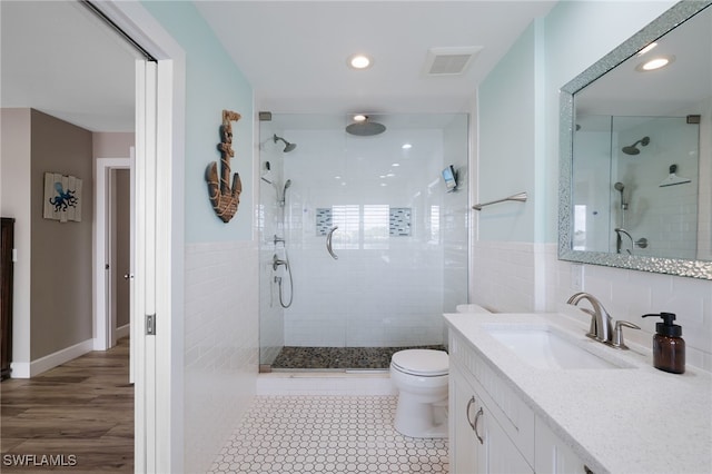 bathroom featuring hardwood / wood-style floors, tiled shower, toilet, and vanity