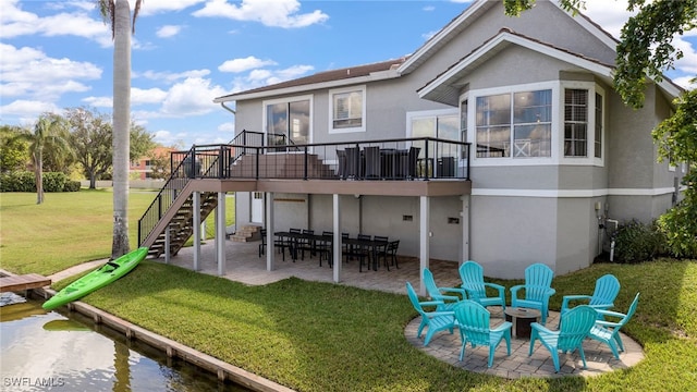 rear view of house featuring a wooden deck, a lawn, and a patio