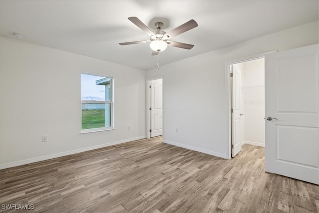 unfurnished bedroom with a closet, light wood-type flooring, a walk in closet, and ceiling fan