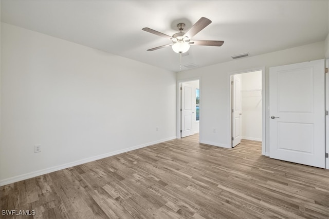 unfurnished bedroom with ceiling fan, a closet, light wood-type flooring, and a spacious closet