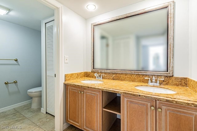 bathroom with toilet, vanity, and tile patterned flooring