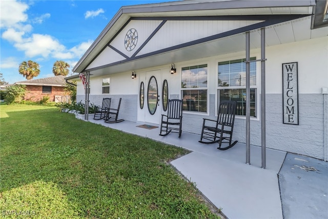 back of property with a lawn and covered porch