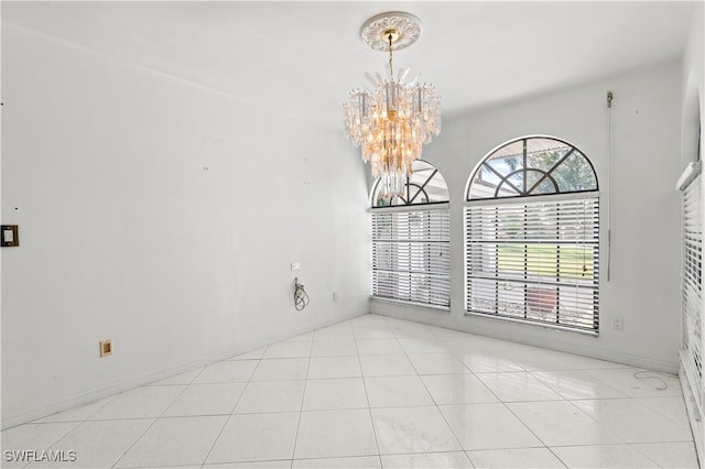 tiled spare room with an inviting chandelier