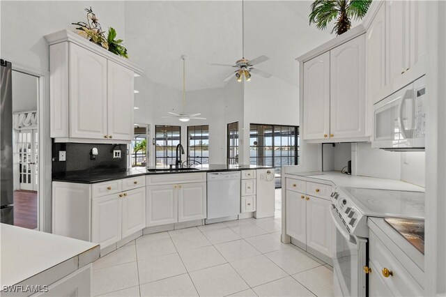 837 SW 2nd Ave, Cape Coral, FL 33991 - kitchen featuring white appliances, ceiling fan, healthy amount of natural light, white cabinetry, and a towering ceiling