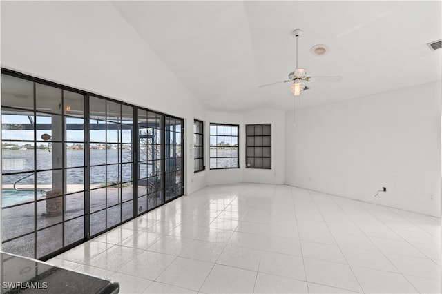 unfurnished room with a high ceiling, ceiling fan, and a water view