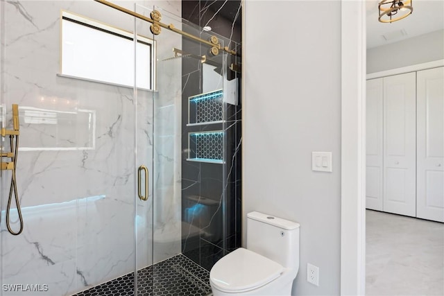 bathroom featuring toilet and a shower with shower door