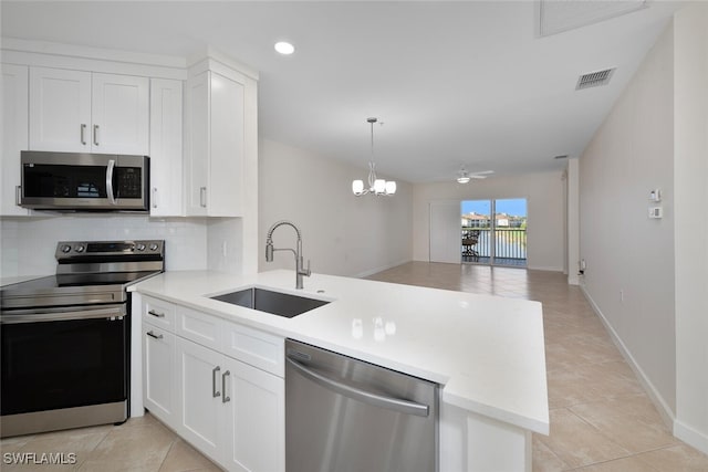 kitchen with kitchen peninsula, appliances with stainless steel finishes, white cabinets, and sink