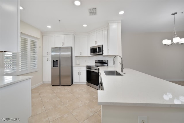 kitchen featuring appliances with stainless steel finishes, sink, an inviting chandelier, white cabinets, and hanging light fixtures