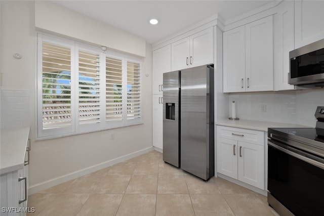 kitchen with white cabinets, appliances with stainless steel finishes, decorative backsplash, and light tile patterned floors