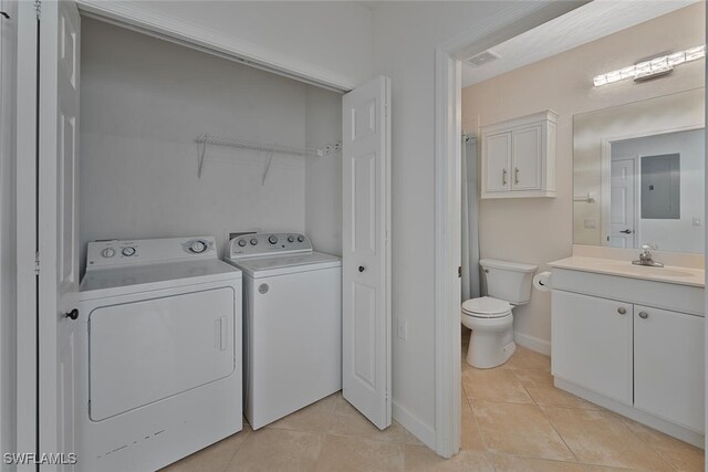 laundry area featuring light tile patterned flooring, separate washer and dryer, and sink