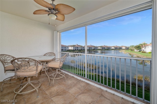 sunroom / solarium featuring a water view and ceiling fan