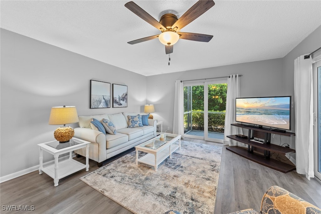 living room featuring ceiling fan, wood-type flooring, and a textured ceiling