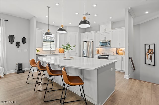 kitchen featuring stainless steel appliances, white cabinets, light hardwood / wood-style flooring, and a center island