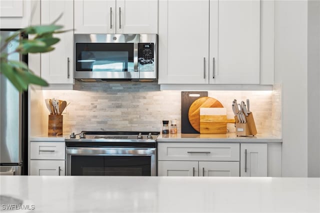 kitchen featuring white cabinets, decorative backsplash, and appliances with stainless steel finishes