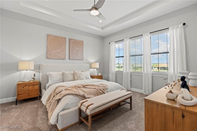 carpeted bedroom with ceiling fan and a raised ceiling