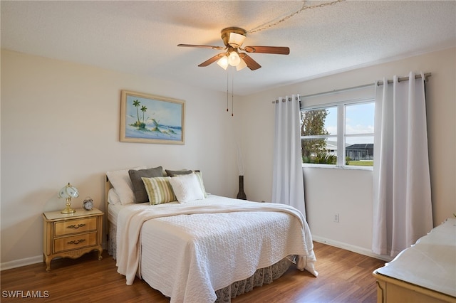 bedroom featuring ceiling fan, dark hardwood / wood-style flooring, and a textured ceiling