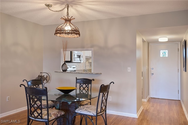 dining area with light wood-type flooring and a textured ceiling