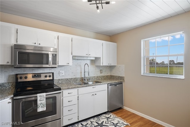 kitchen with light stone countertops, appliances with stainless steel finishes, white cabinetry, and sink