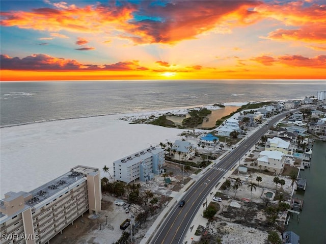 aerial view at dusk with a water view and a view of the beach