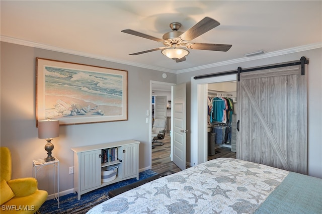 bedroom featuring ceiling fan, a barn door, ornamental molding, and a closet