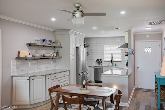 kitchen with sink, crown molding, light wood-type flooring, appliances with stainless steel finishes, and white cabinetry