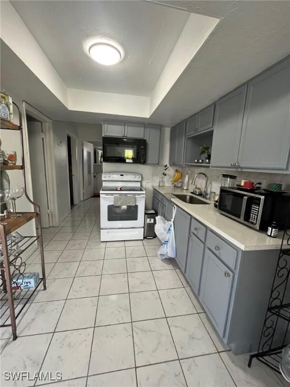 kitchen with a raised ceiling, sink, gray cabinets, and white range with electric cooktop