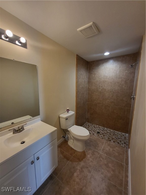 bathroom featuring tiled shower, vanity, tile patterned floors, and toilet