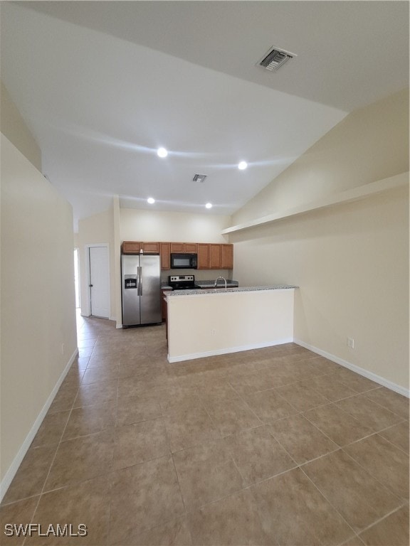 kitchen with stainless steel appliances, light tile patterned flooring, sink, kitchen peninsula, and vaulted ceiling