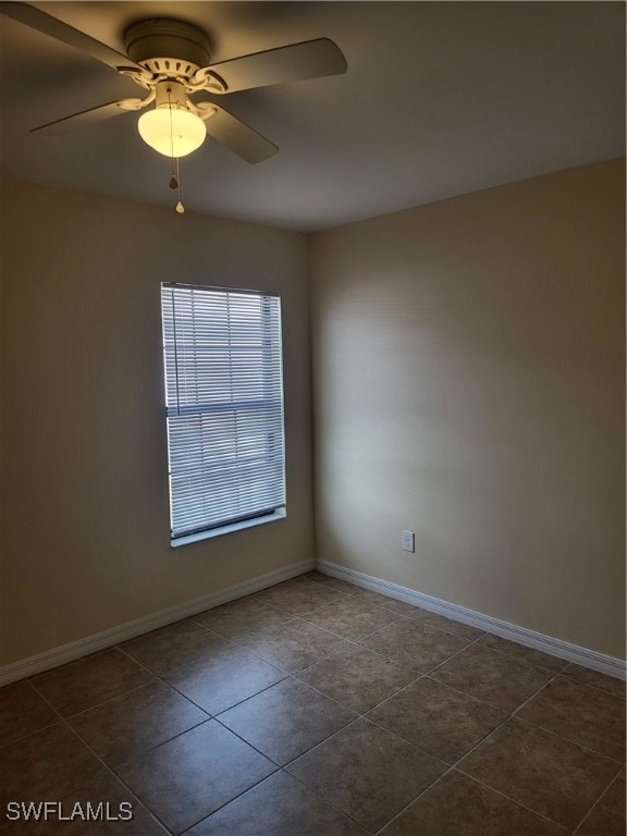 spare room featuring ceiling fan and dark tile patterned floors