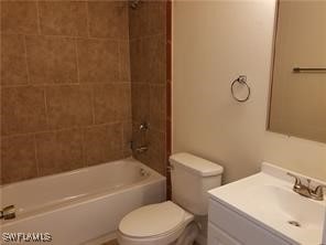 full bathroom with vanity, tiled shower / bath, and toilet