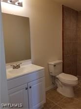 bathroom with toilet, vanity, and tile patterned floors