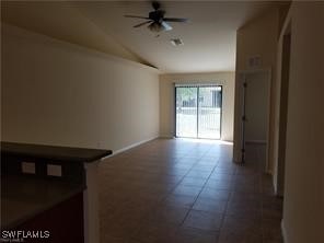 tiled spare room with lofted ceiling and ceiling fan