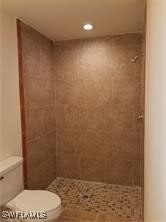 bathroom featuring toilet and a tile shower