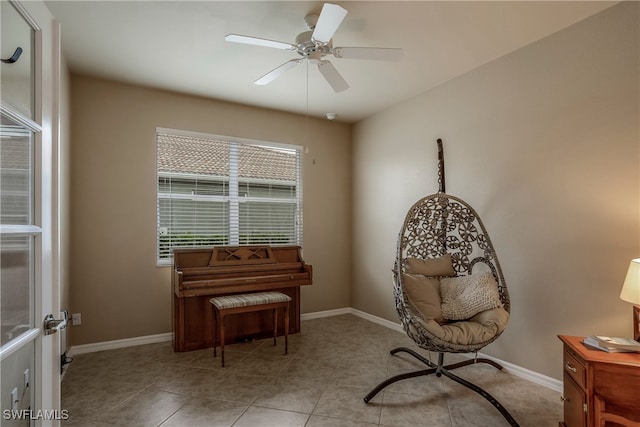 living area featuring baseboards, a ceiling fan, and light tile patterned flooring