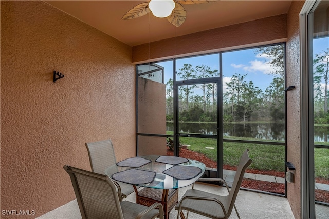 sunroom / solarium featuring ceiling fan and a water view