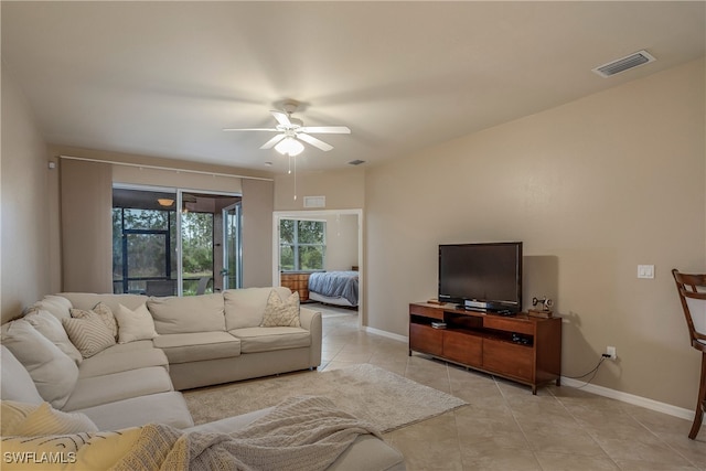 living area with light tile patterned floors, a ceiling fan, visible vents, and baseboards