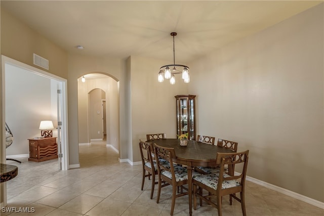 dining area with light tile patterned floors, baseboards, visible vents, and arched walkways