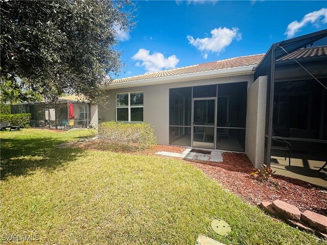 rear view of property with a lawn, a lanai, and stucco siding