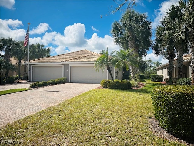 view of front of home with decorative driveway, an attached garage, a tiled roof, and a front lawn