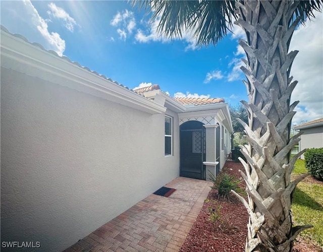 entrance to property with a tiled roof and stucco siding