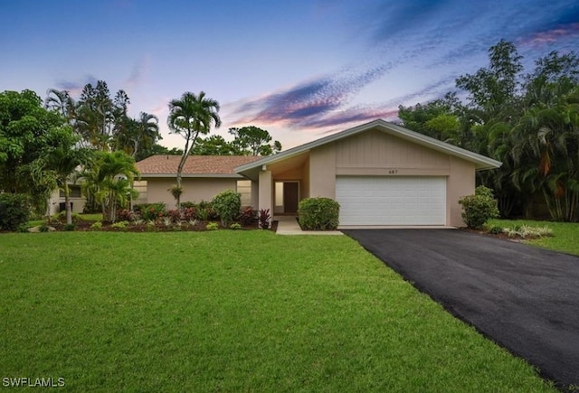 single story home featuring a garage and a lawn